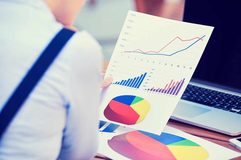 A person reviewing financial reports and charts at a desk